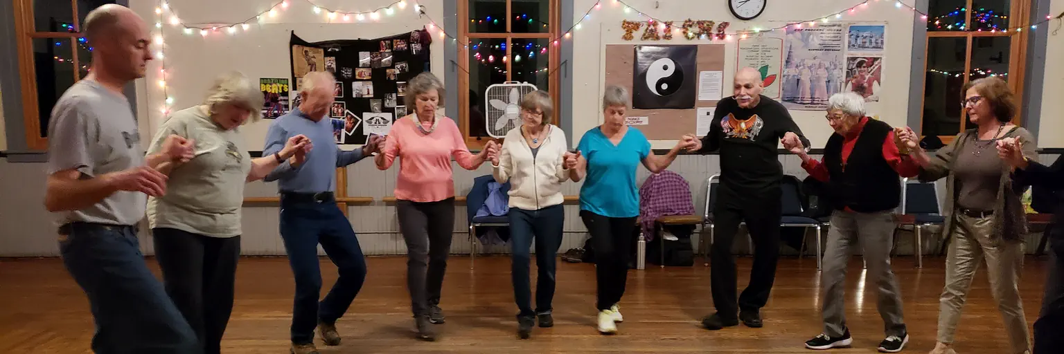 A group of people dancing in a semi-circle with connected hands.